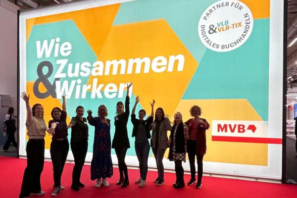 Team Digital vor einer Messewand mit der Aufschrift "Wie Zusammen und Wirken".