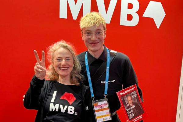 Susanne Fuchs und ihr Sohn vor dem MVB Logo am Stand auf der Leipziger Buchmesse.